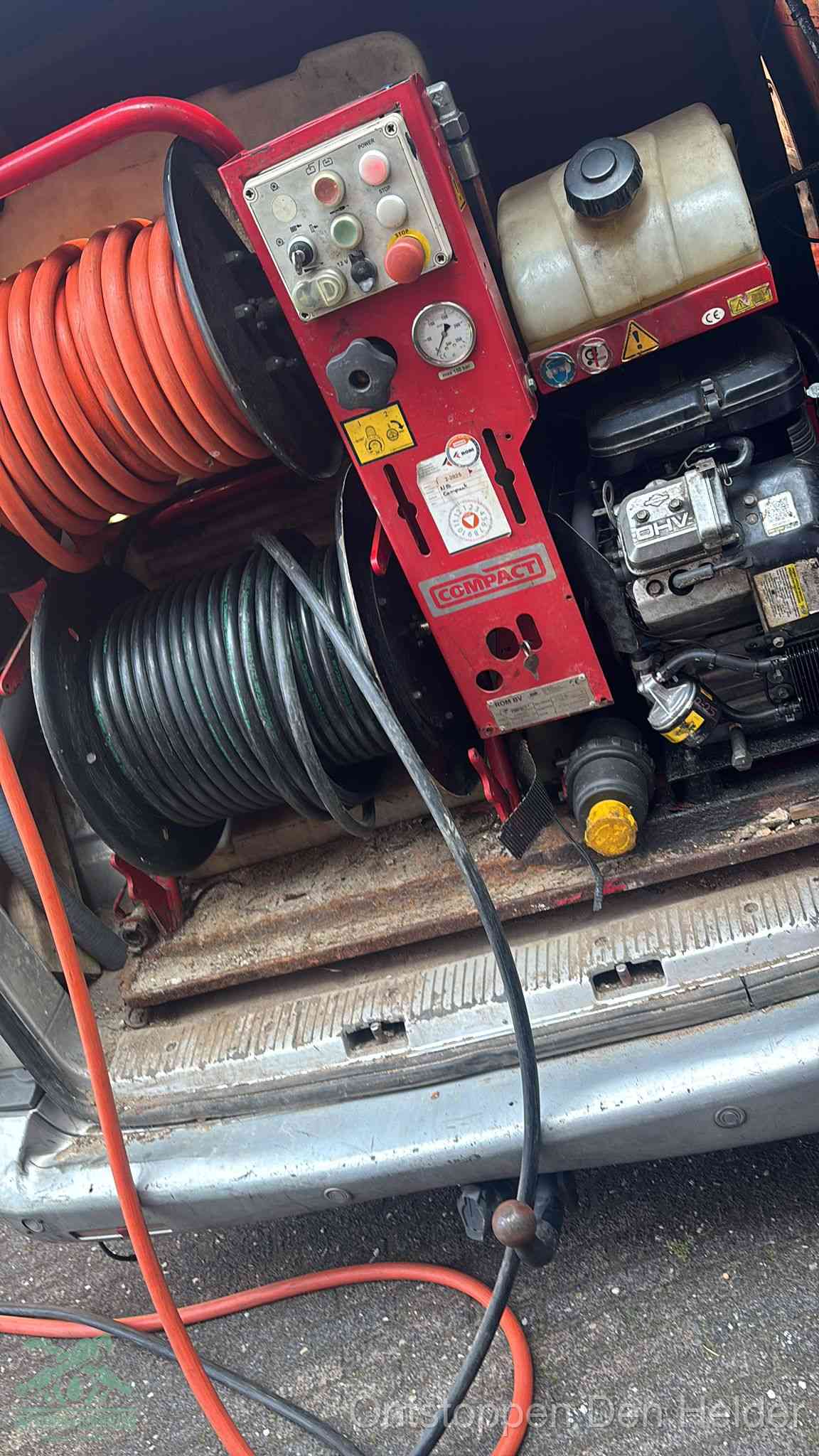 Een rood hogedruk-rioolreinigingstoestel in de laadbak van de bedrijfsbus, apparatuur voor een hardnekkige afvoerverstopping in Den Helder