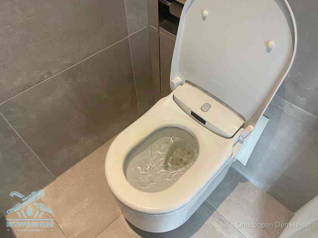 Een toiletpot vol troebel water met drijvend papier en restanten, de meest voorkomende oorzaak van een verstopte wc in Den Helder