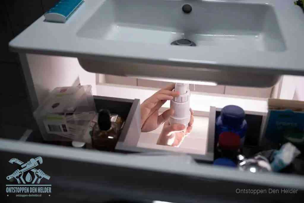 Een pompfles met zeep boven een wastafel in de toiletruimte, de warm water en afwasmiddel-methode om de wc te ontstoppen in Den Helder