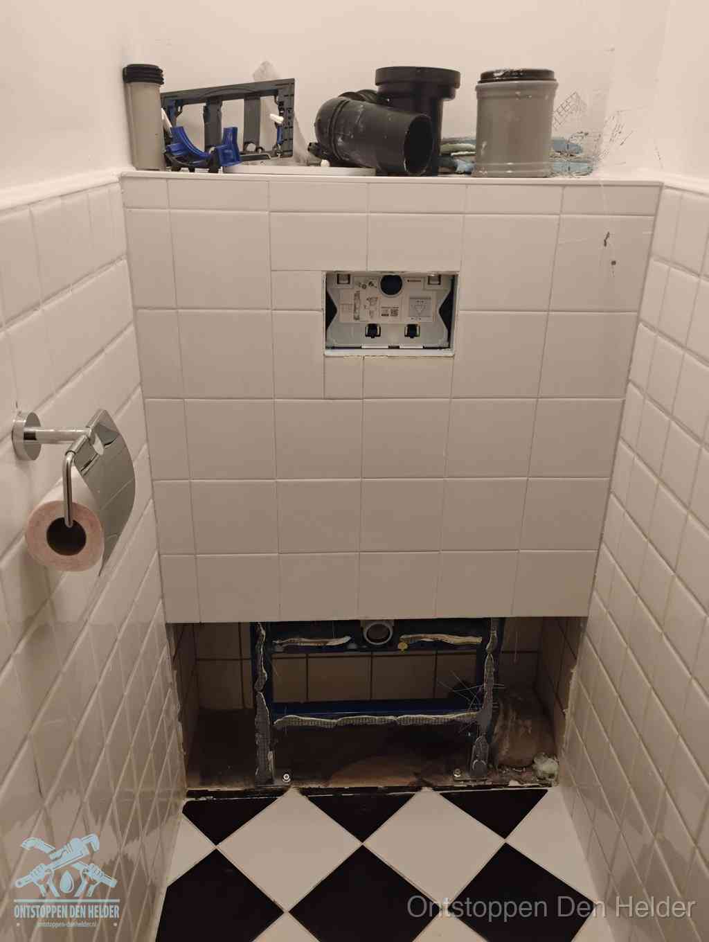 Een toiletruimte waar het hangtoilet en de inbouwreservoir-onderdelen zijn vrijgelegd voor onderhoud, periodiek nazicht voorkomt een wc-verstopping in Den Helder